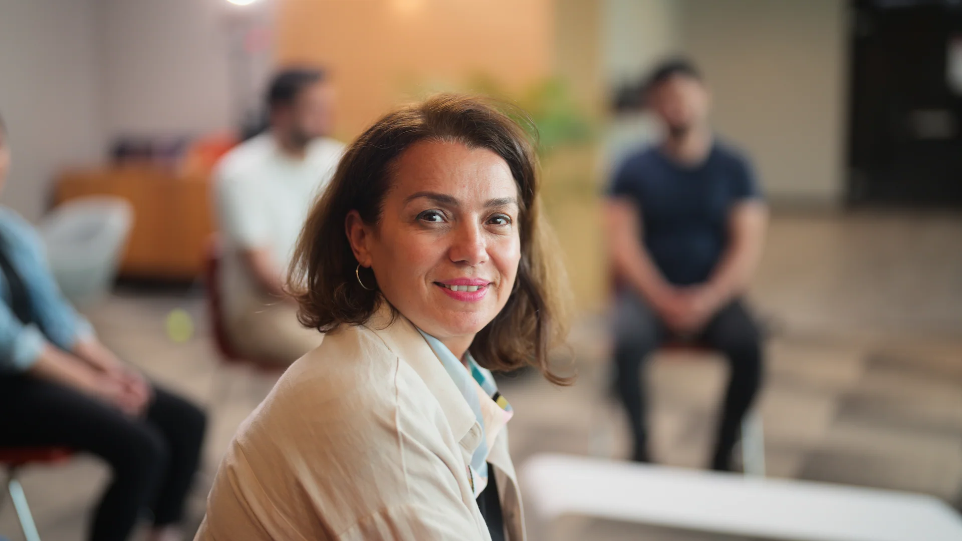 female course facilitator smiling with trainees in the background