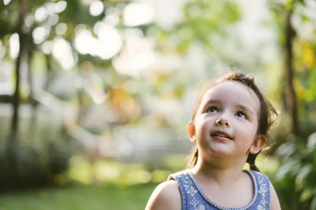 Girl looking up at trees
