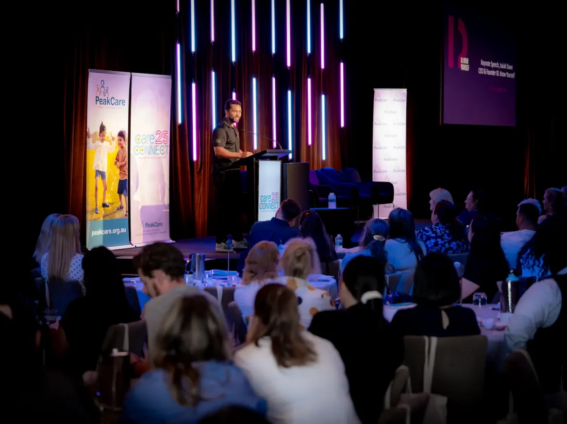 A presenter speak to a large venue full of people