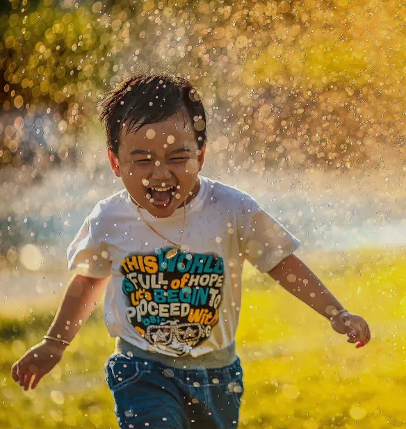 Child running through a sprinkler